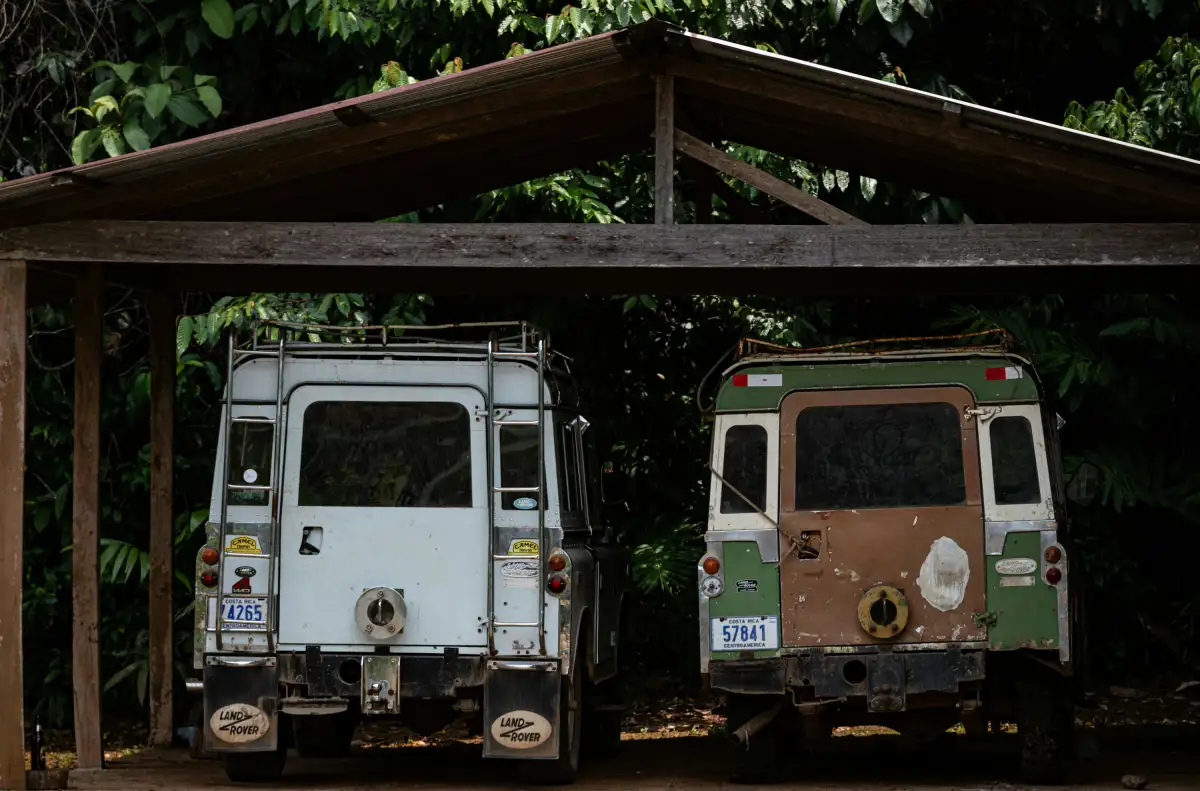A couple of trucks parked under a wooden structure